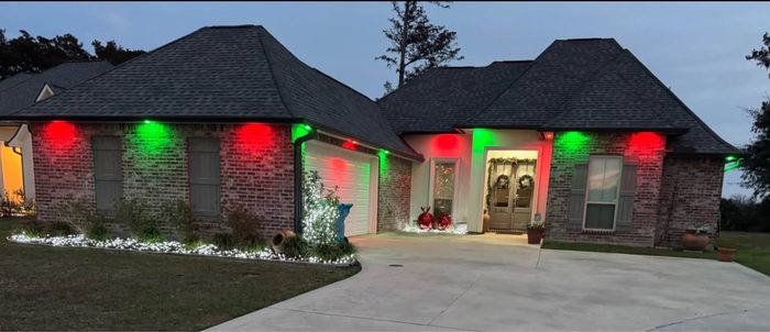 Red and green holiday lighting installed on a brick home by TK Electric